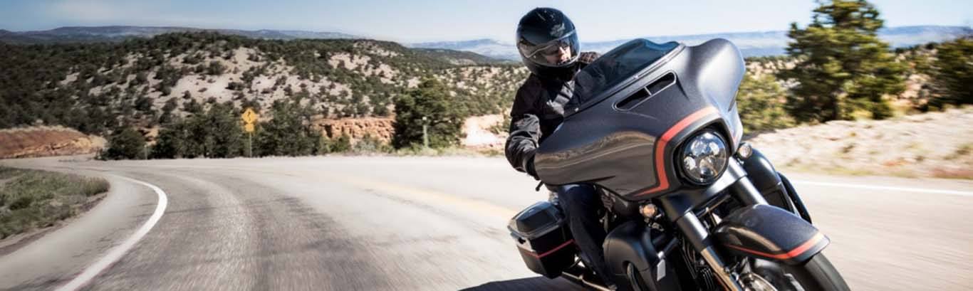 Image of guy driving a Harley-Davidson motorcycle on s curved road